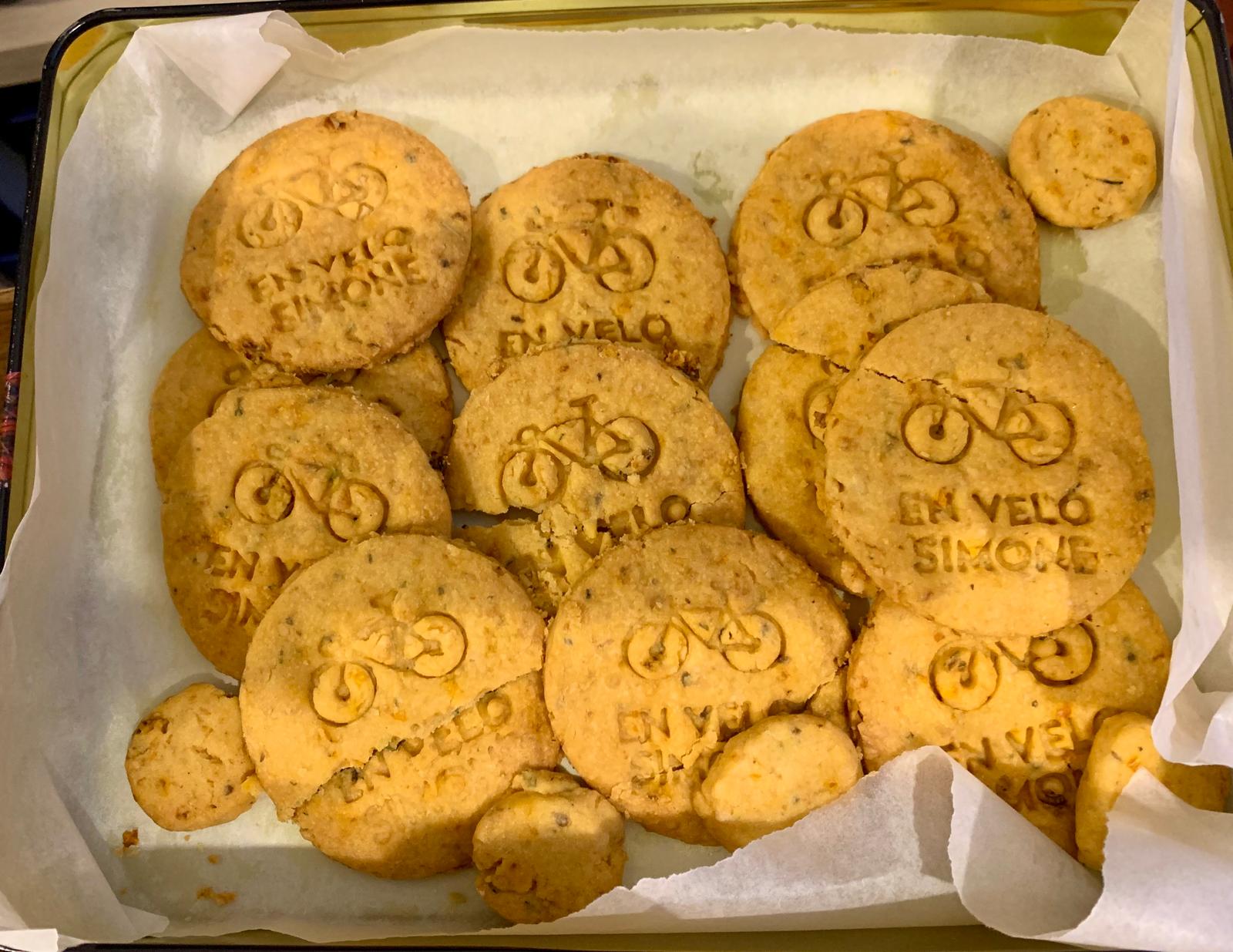 Biscuits artisanaux dorés en forme de sablés, décorés d’un vélo et de l’inscription « En Vélo Simone », disposés sur une plaque de cuisson recouverte de papier sulfurisé.